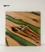 Orologio da parete di design realizzato in legno massello di castagno scortecciato immerso in resina verde marmorizzata