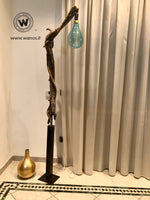 Design floor lamp made of raw wood on a corten-effect iron structure.