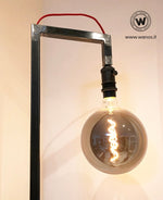 Piantana da terra stile industrial di design con struttura in ferro grezzo naturale.