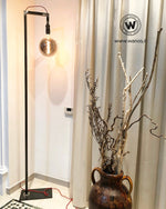 Piantana da terra stile industrial di design con struttura in ferro grezzo naturale.