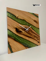 Design wall clock made of solid debarked chestnut wood immersed in green marbled resin