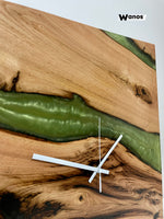 Design wall clock made of solid debarked chestnut wood immersed in green marbled resin