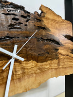 Design wall clock made of solid centuries-old olive wood on a metal structure.